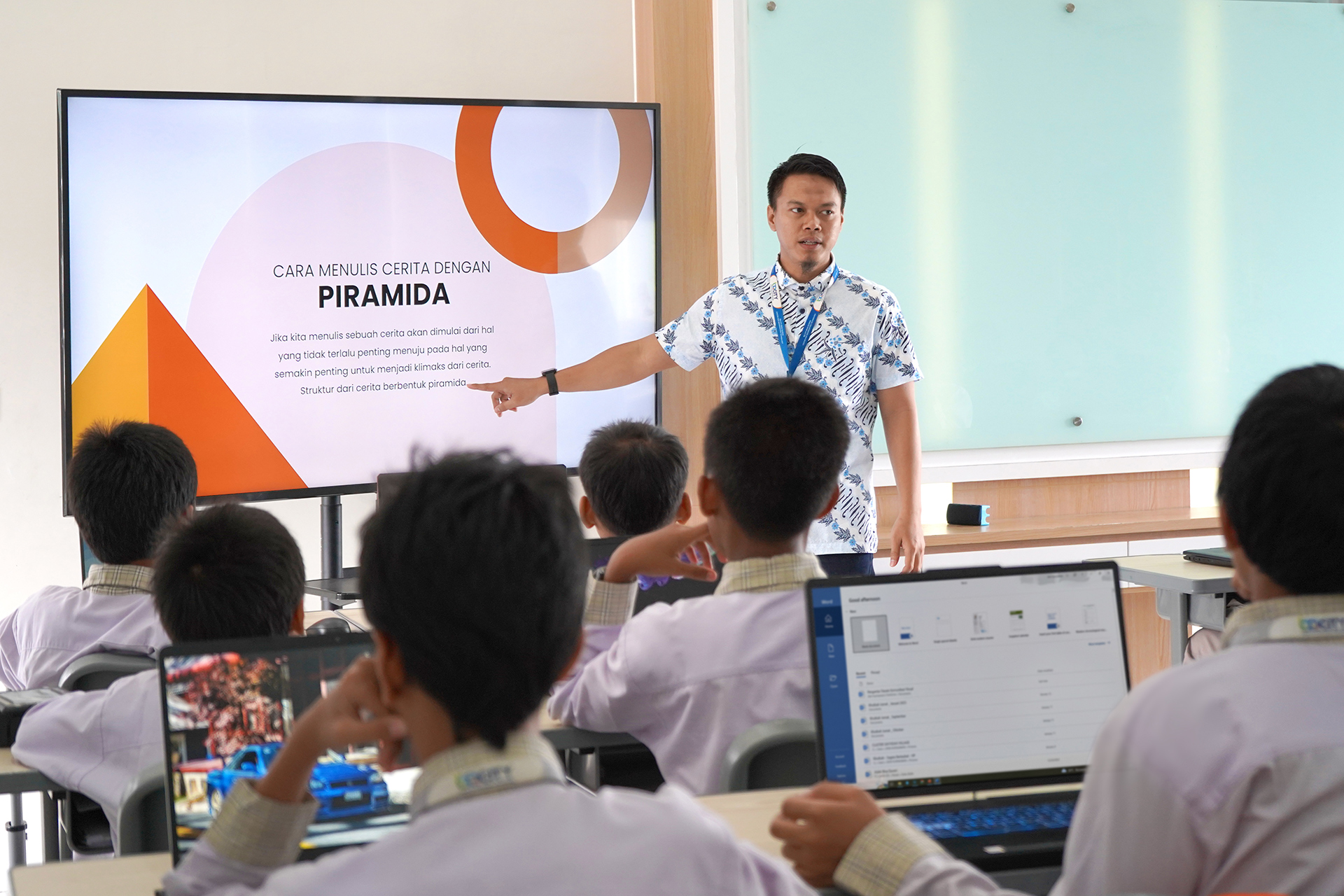 Guru menjelaskan materi lewat layar presentasi di kelas